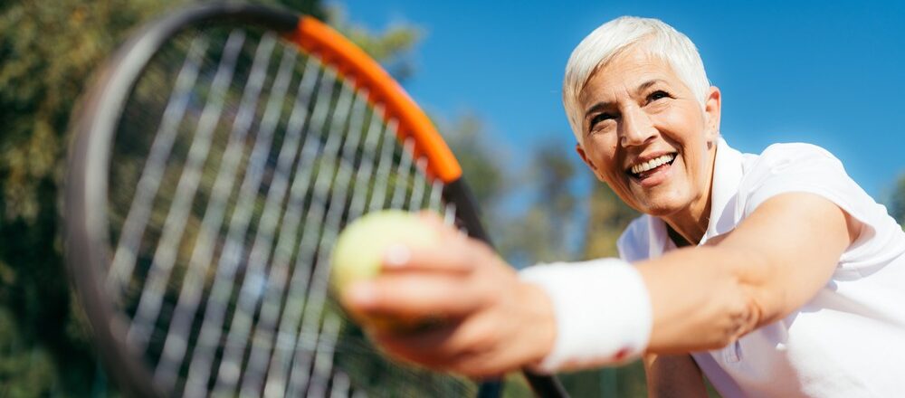 Active senior woman playing tennis outdoors